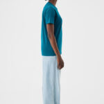 Femme de profil en t-shirt turquoise et jean