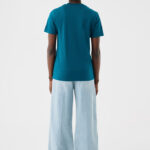 Femme de dos en t-shirt vert et pantalon large