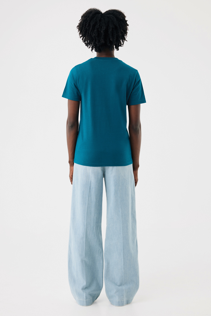 Femme de dos en t-shirt vert et pantalon large