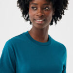 Femme souriante aux cheveux bouclés en t-shirt bleu