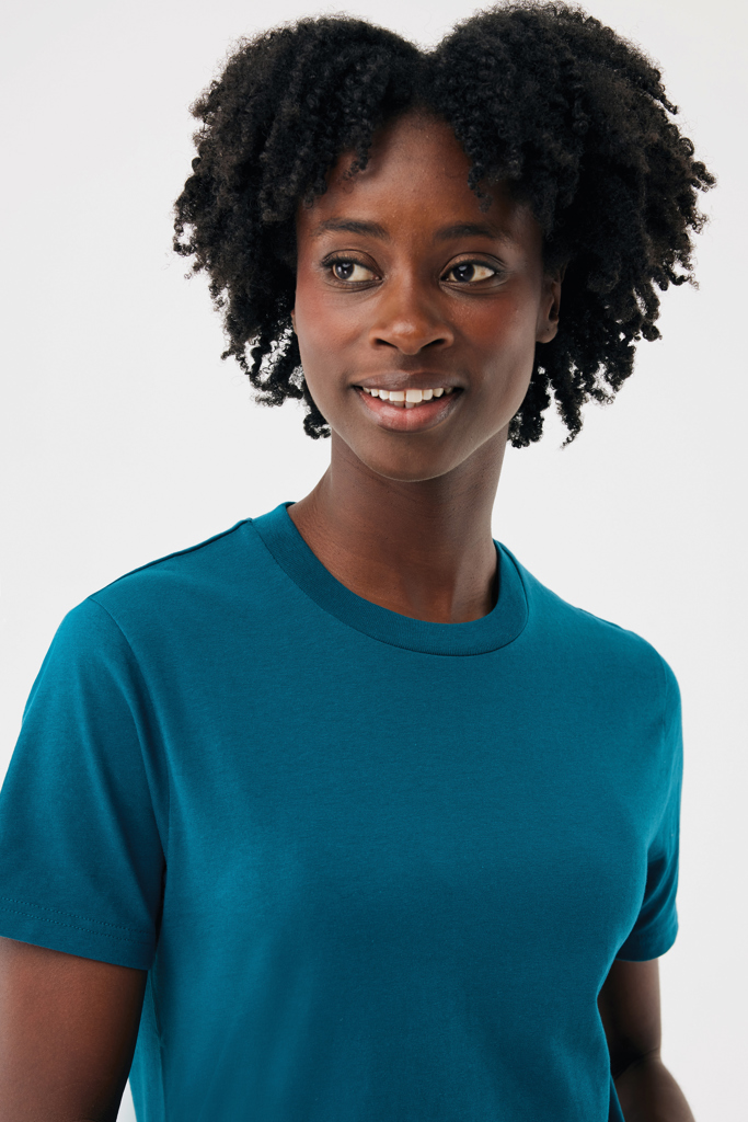 Femme souriante aux cheveux bouclés en t-shirt bleu