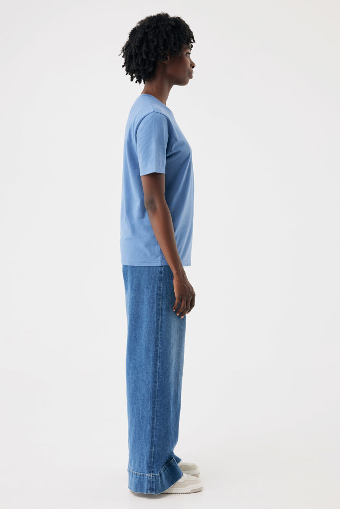 Femme de profil en t-shirt bleu et jean