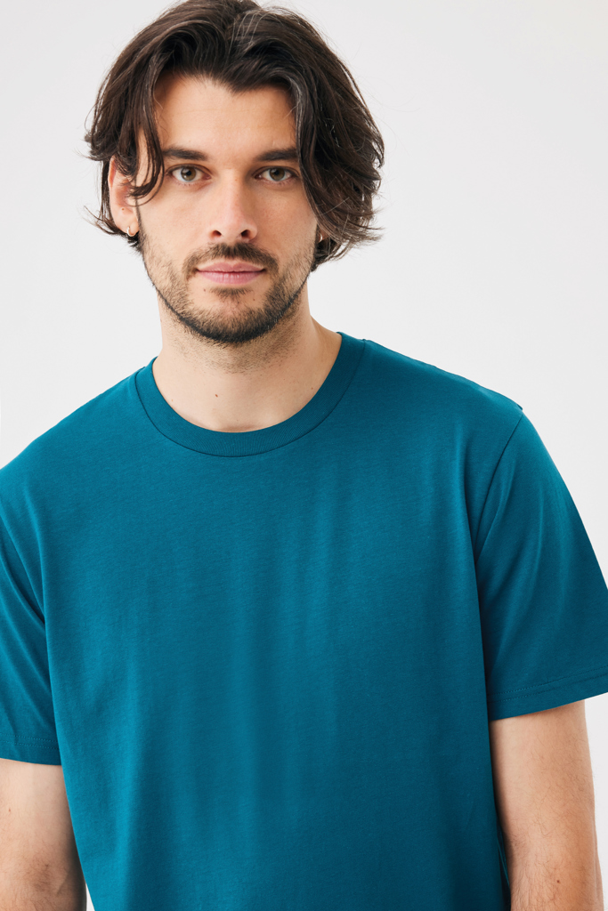 Homme aux cheveux mi-longs en t-shirt bleu pétrole