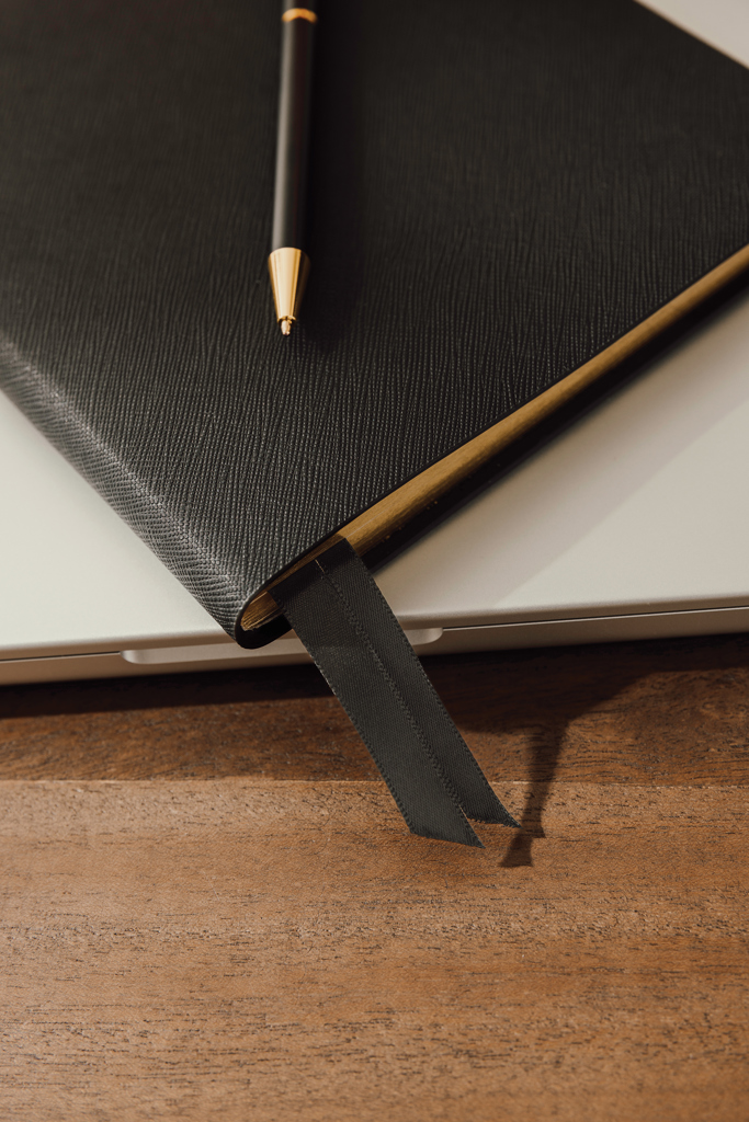 Carnet noir avec stylo sur bureau en bois