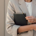 Femme en blazer beige tenant carnet noir