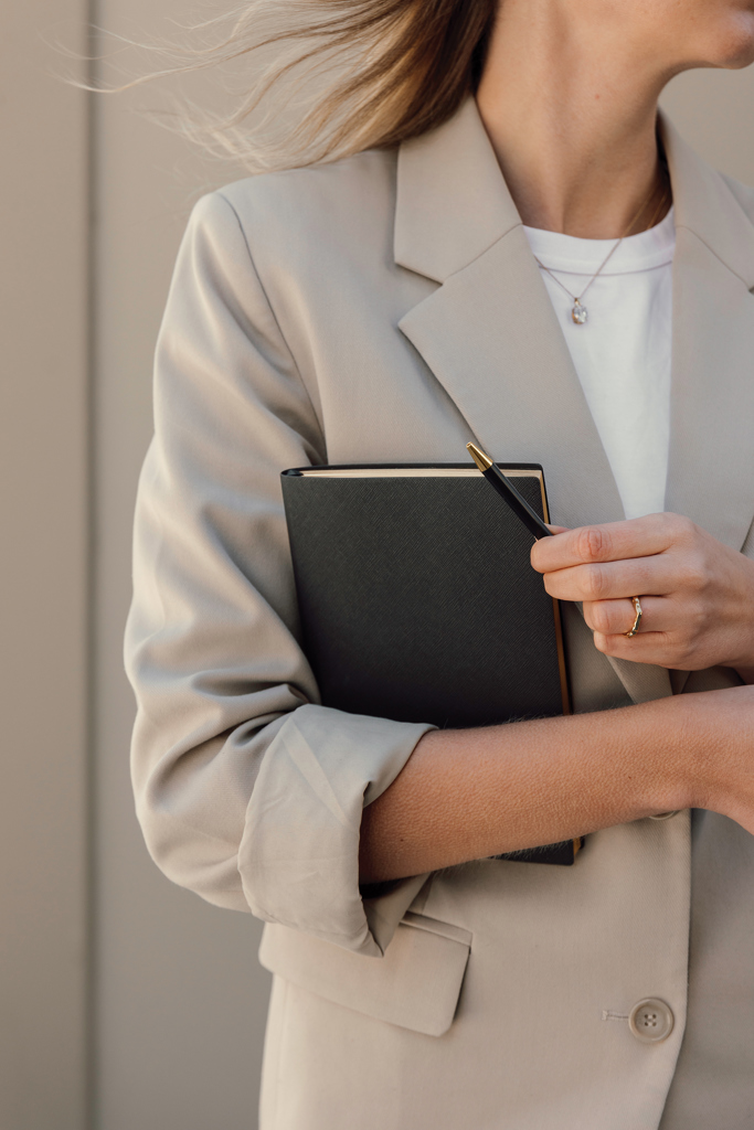 Femme en blazer beige tenant carnet noir