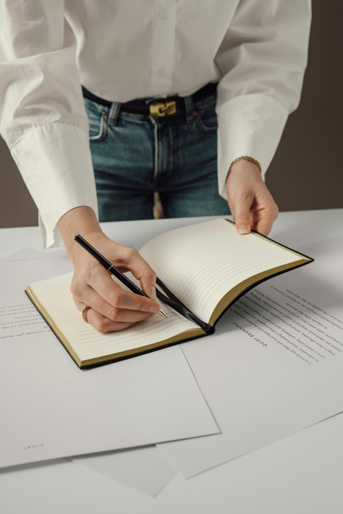 Personne écrivant dans un carnet sur un bureau