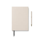 Carnet beige avec stylo assorti sur fond blanc