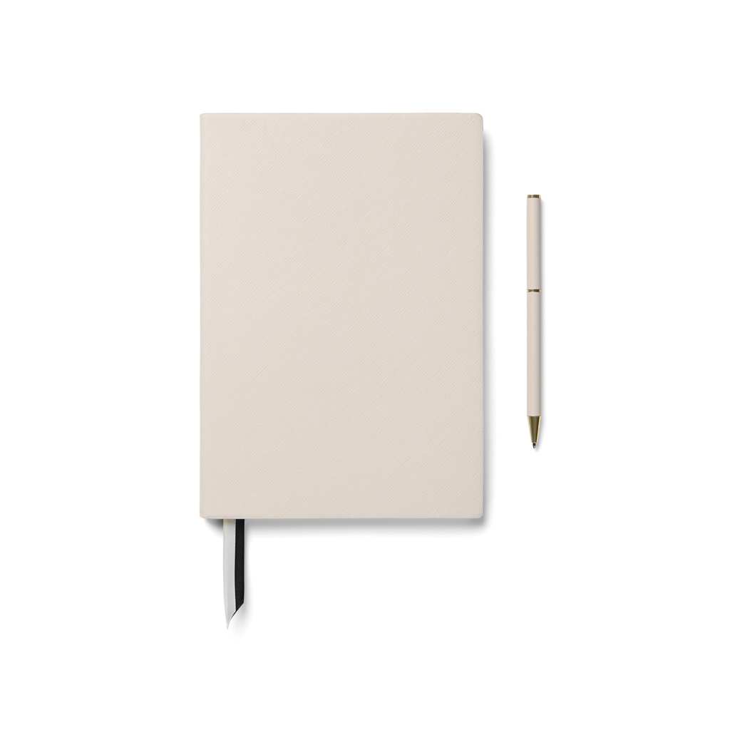 Carnet beige avec stylo assorti sur fond blanc