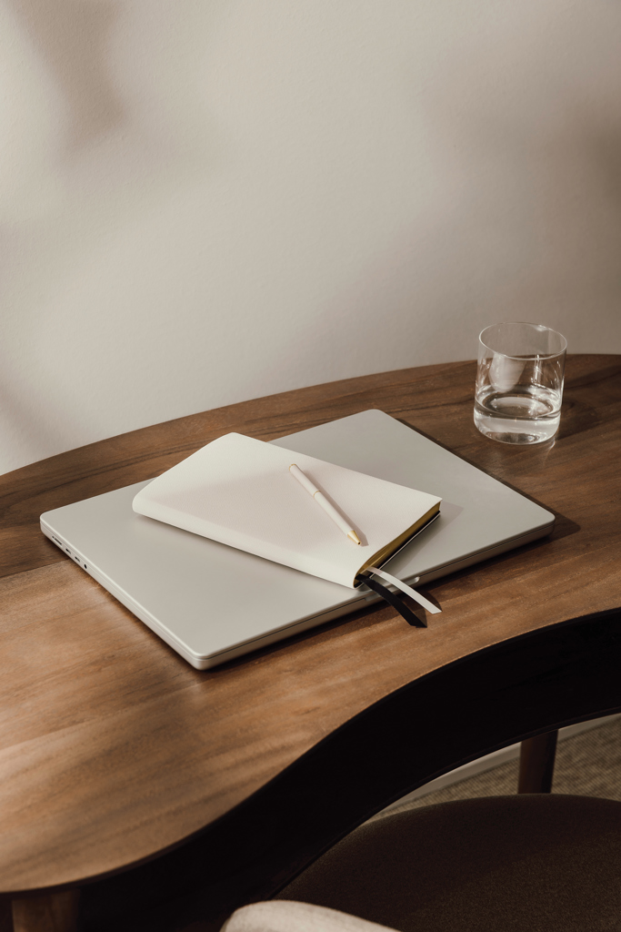 Ordinateur portable, carnet et verre d’eau sur bureau