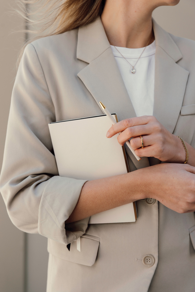 Femme élégante tenant carnet et stylo beige