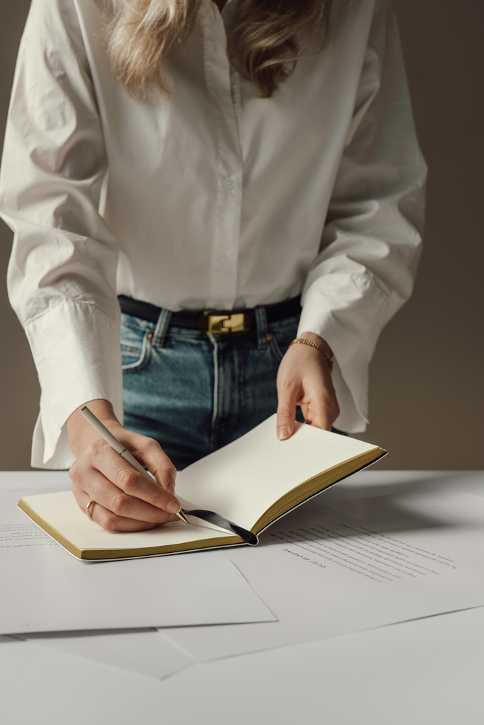 Personne écrivant dans un carnet sur un bureau