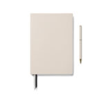 Carnet beige avec stylo assorti sur fond blanc
