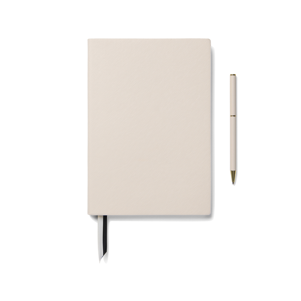 Carnet beige avec stylo assorti sur fond blanc