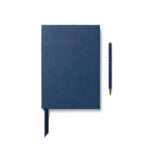 Carnet bleu avec stylo assorti sur fond blanc