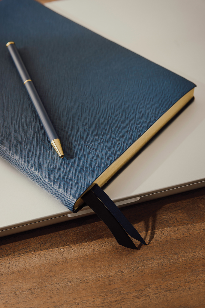 Carnet bleu avec stylo sur ordinateur portable
