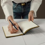 Personne écrivant dans un carnet sur un bureau