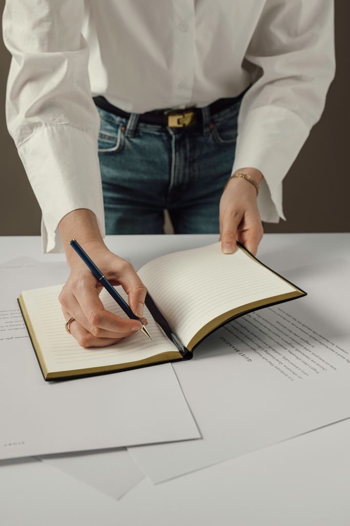 Personne écrivant dans un carnet sur un bureau